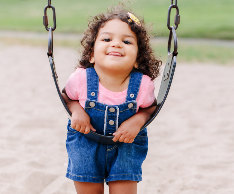 little girl hangs on swing