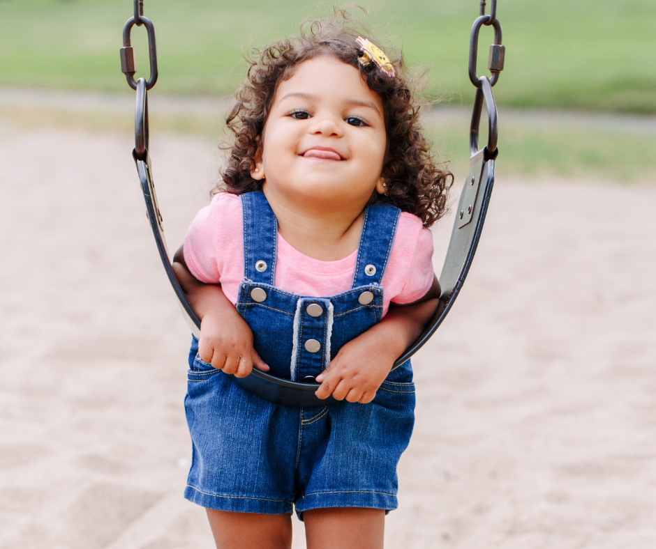 little girl hangs on swing